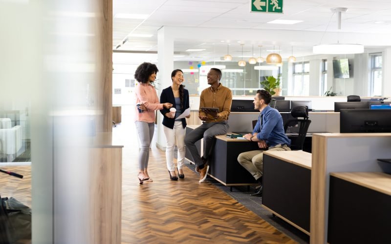 Diverse businesspeople in office talking and laughing. Business, corporation, working in office and cooperation concept.